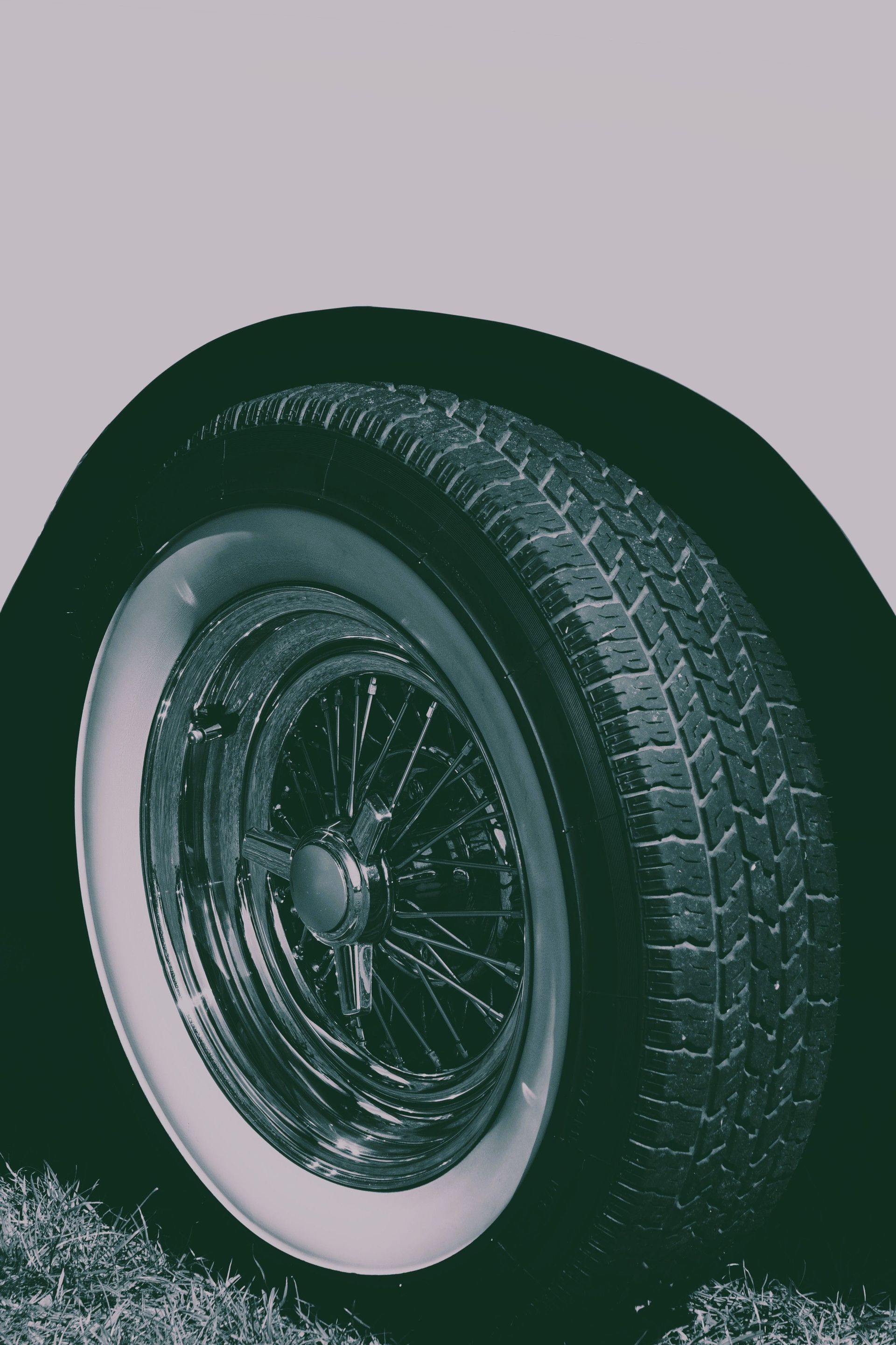 Close-up of a chrome-spoked vintage car wheel with whitewall tires, showcasing retro automotive design.